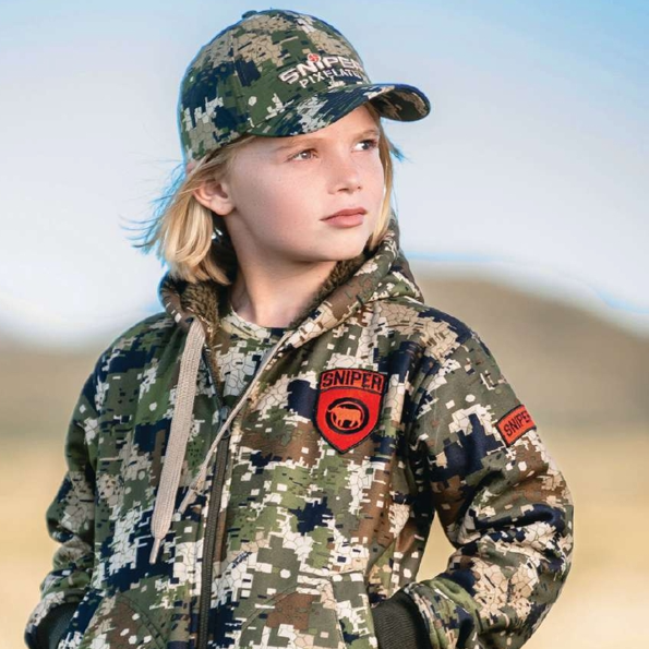 Child wearing a camouflage jacket and cap with 'Sniper' branding outdoors.